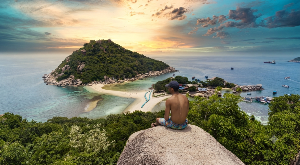 Koh Tao Travel Guide: Diving, Snorkeling & Island Life Traveler sitting on a rock overlooking the twin sandbars of Koh Nang Yuan island at sunset, Koh Tao, Thailand
